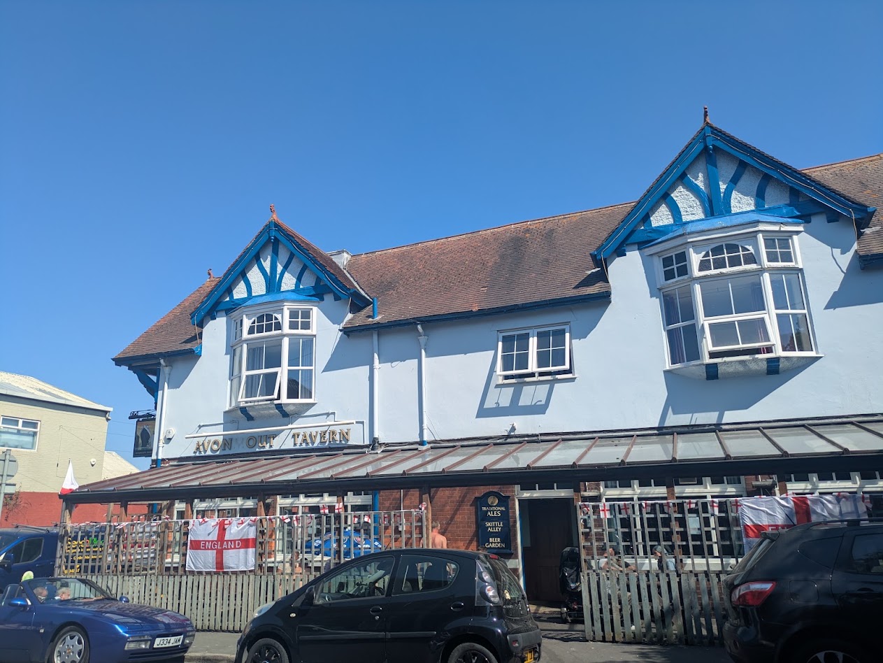 A picture of the outside, two letters are missing so it spells 'Avon Out Tavern'. It has a lot of England flags