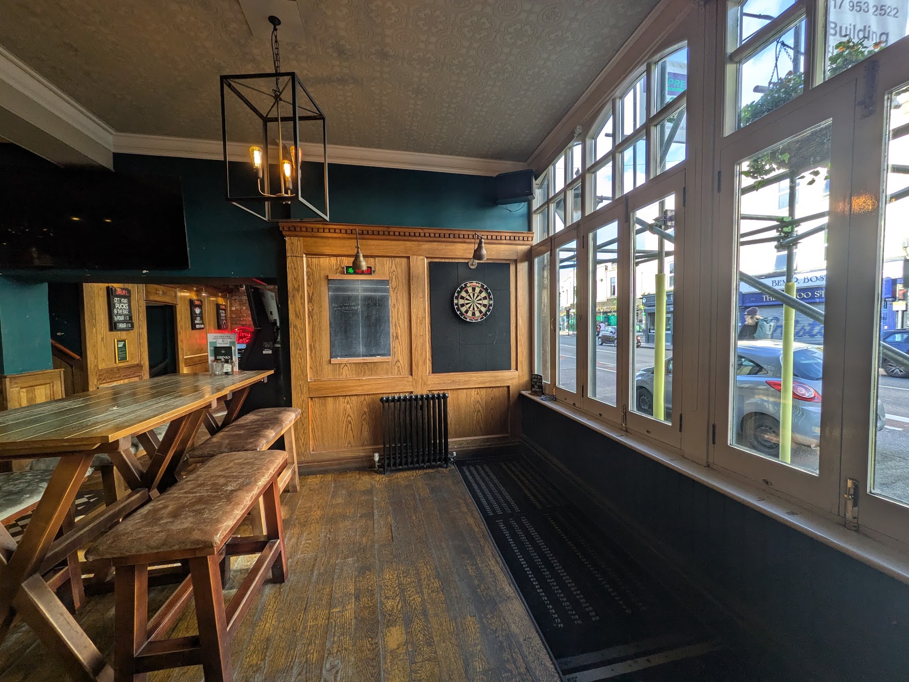 A wider shot of the oche showing the chalkboard, dartboard and windows
