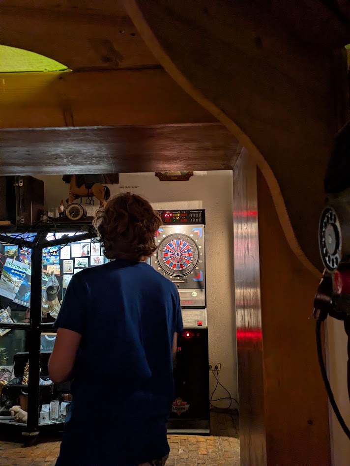 A shot from behind of Jrat throwing darts