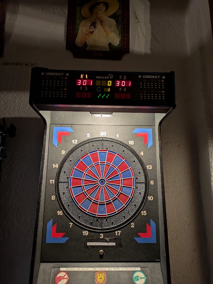 A close up of the board, an arcade machine with digital scoring at the top, and blue and red segments on the board