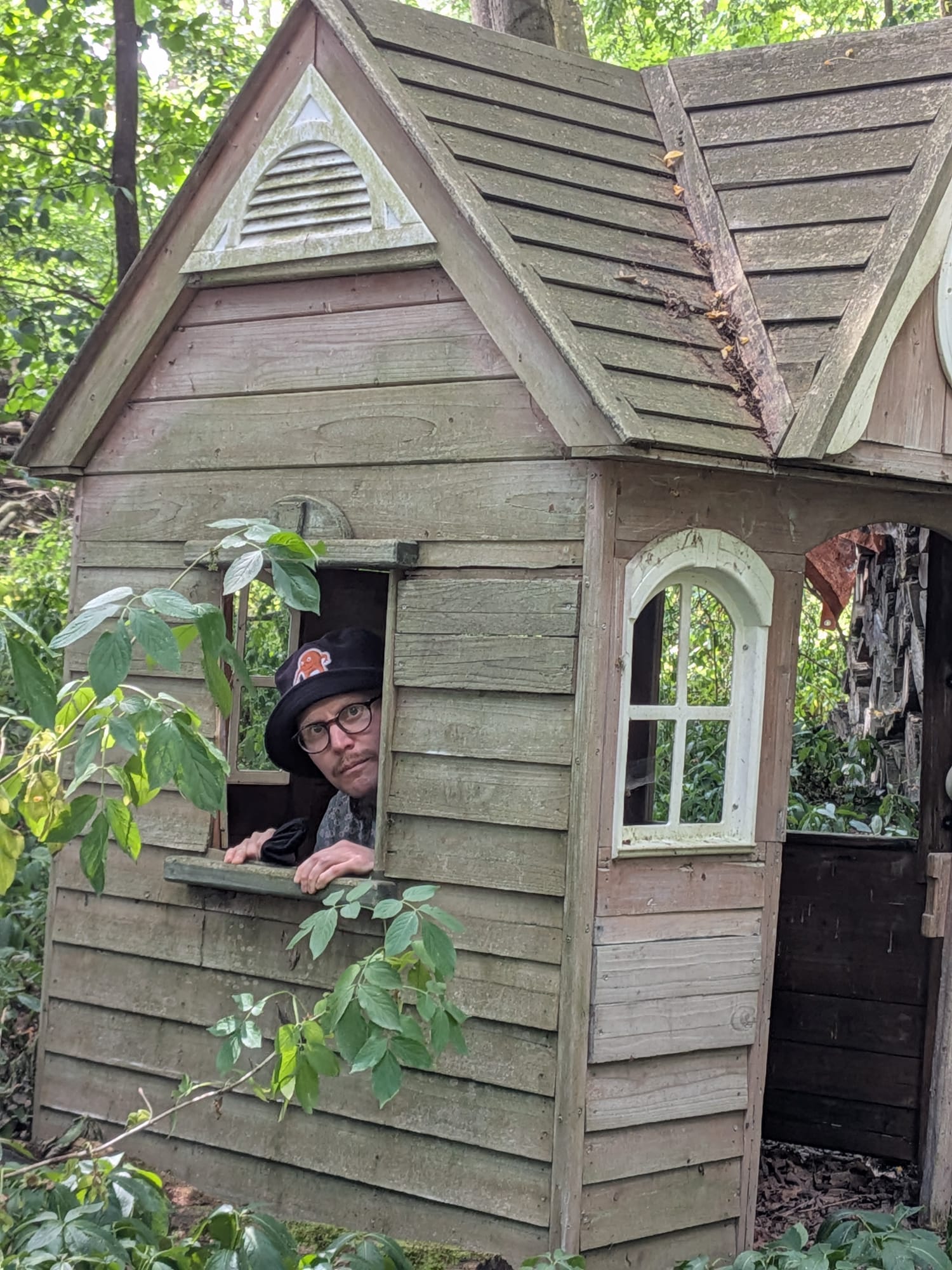 A picture of me wearing a bucket hat in a wendy house we found in the middle of some woods