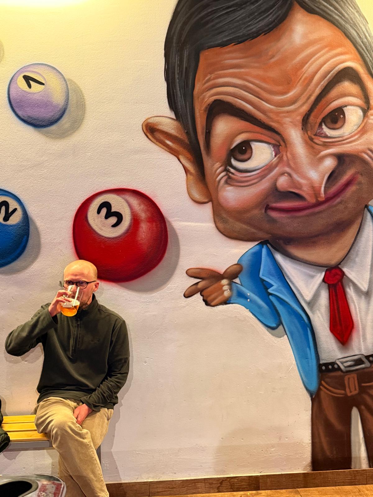 A caricature mural of Mr Bean with me sat below drinking a pint of lager