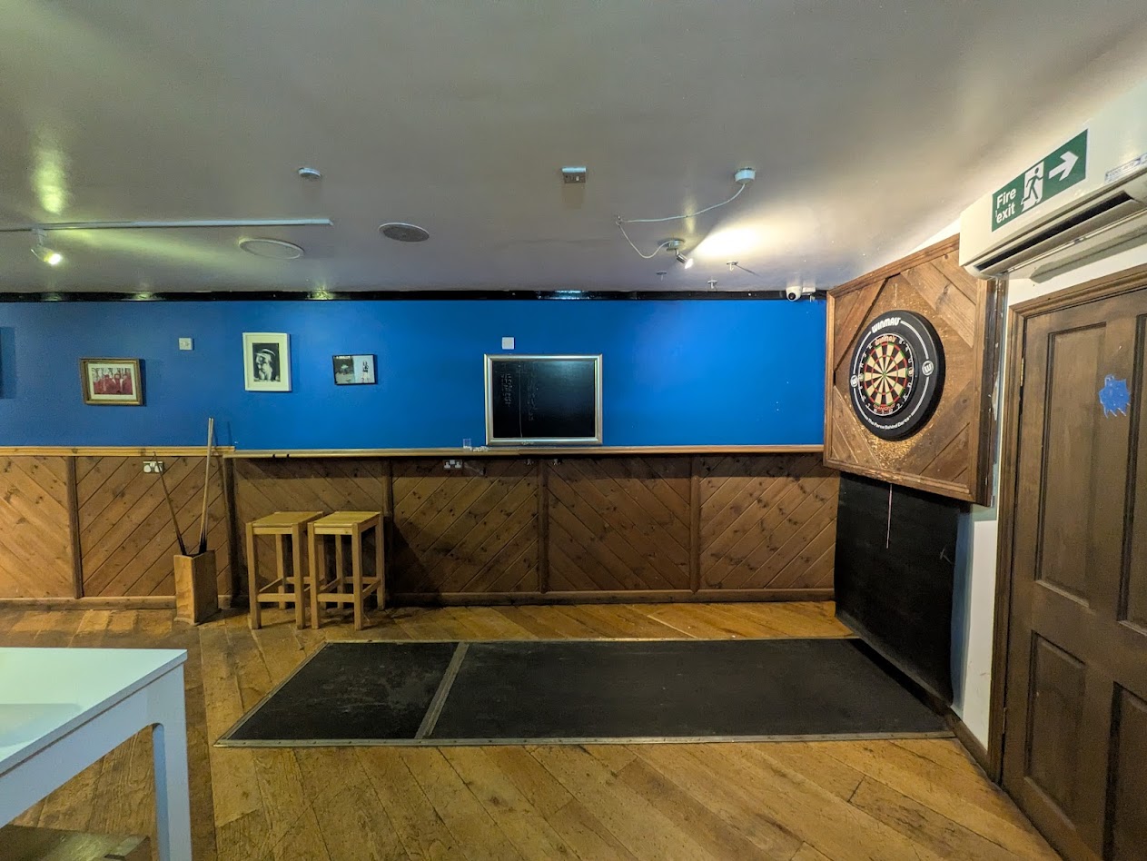 a wide shot of the oche, showing the funny cupboard like mount the board is on