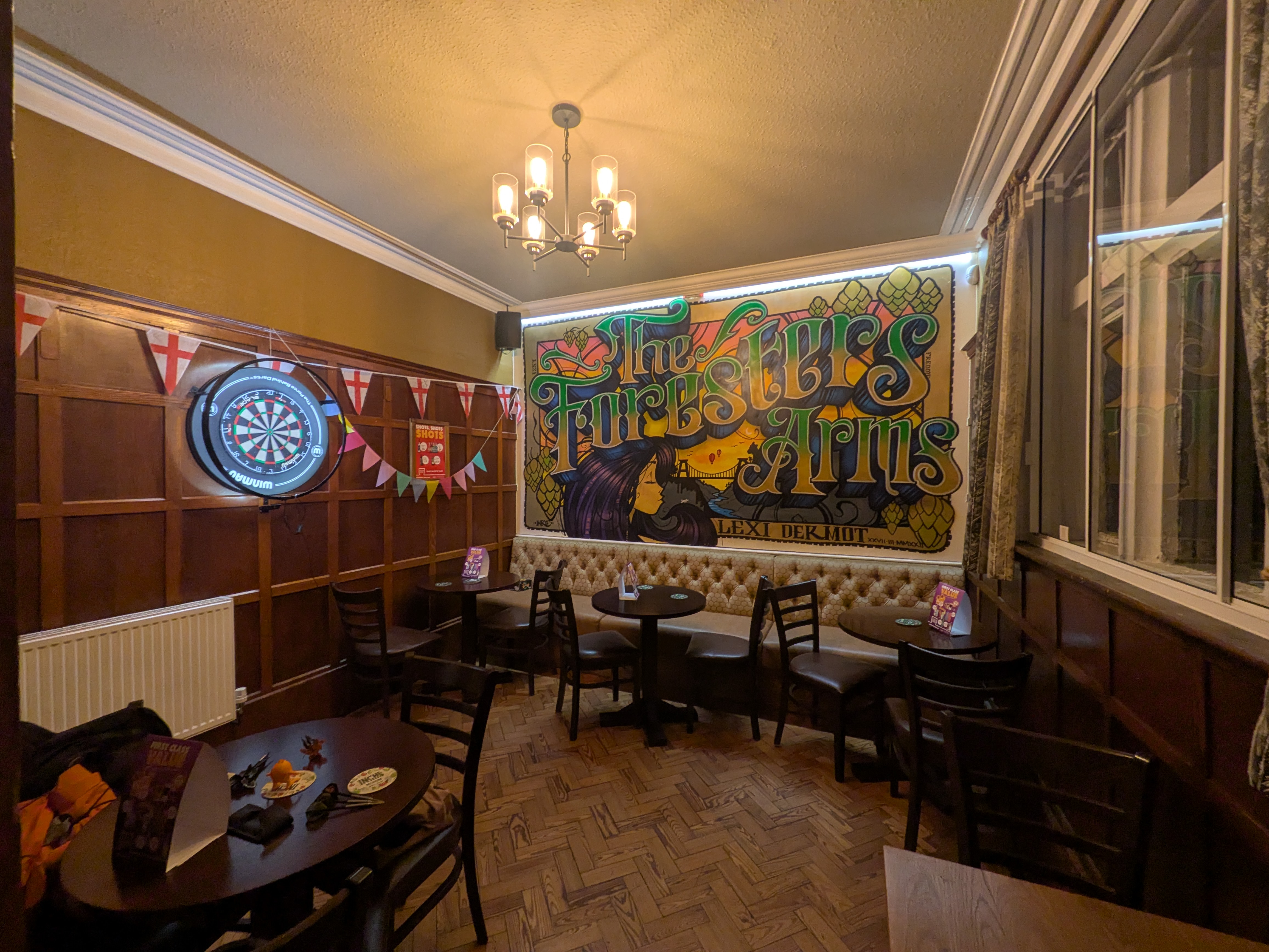 A wide picture of the room, showing a long bench ont the back wall with tables and chairs, and england + regular bunting