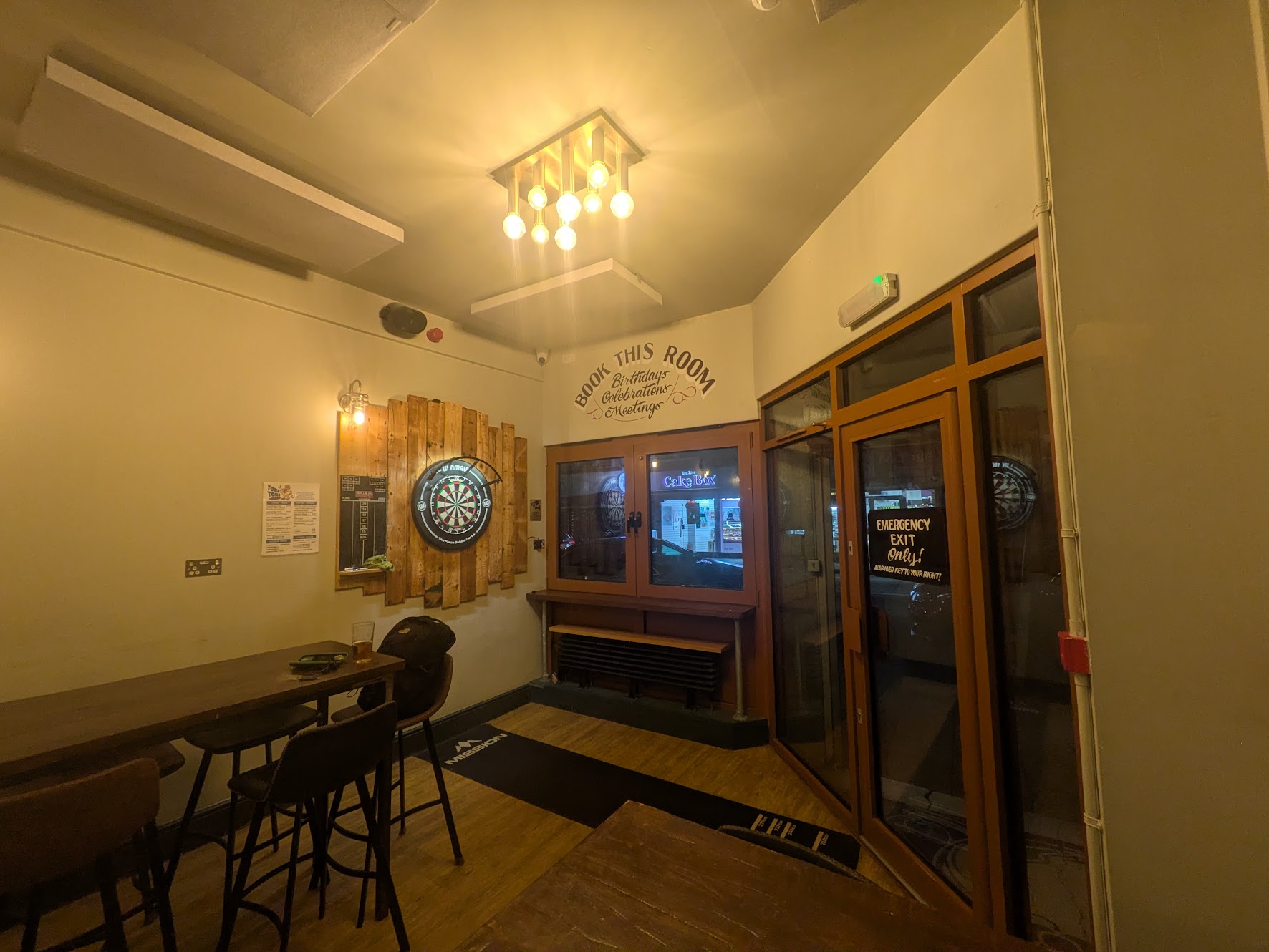 A wider shot of the function room with the dartboard, showing the tables, and that the oche is pressed against the window, making it a bit tight for throwers that prefer the right hand side of the line