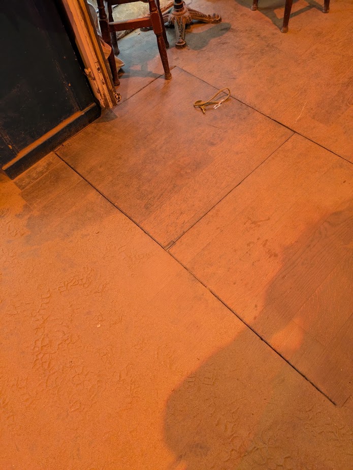 The oche is a wooden hatch leading to the cellar, separating the sandy floor of the rest of the bar