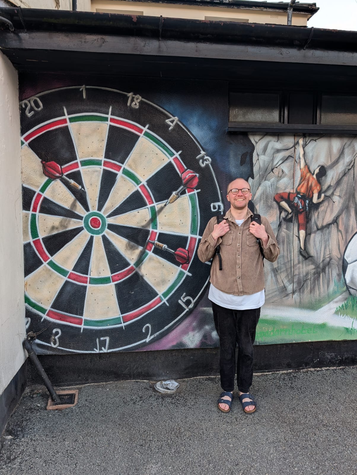 Me stood next to a large mural of a dartboard