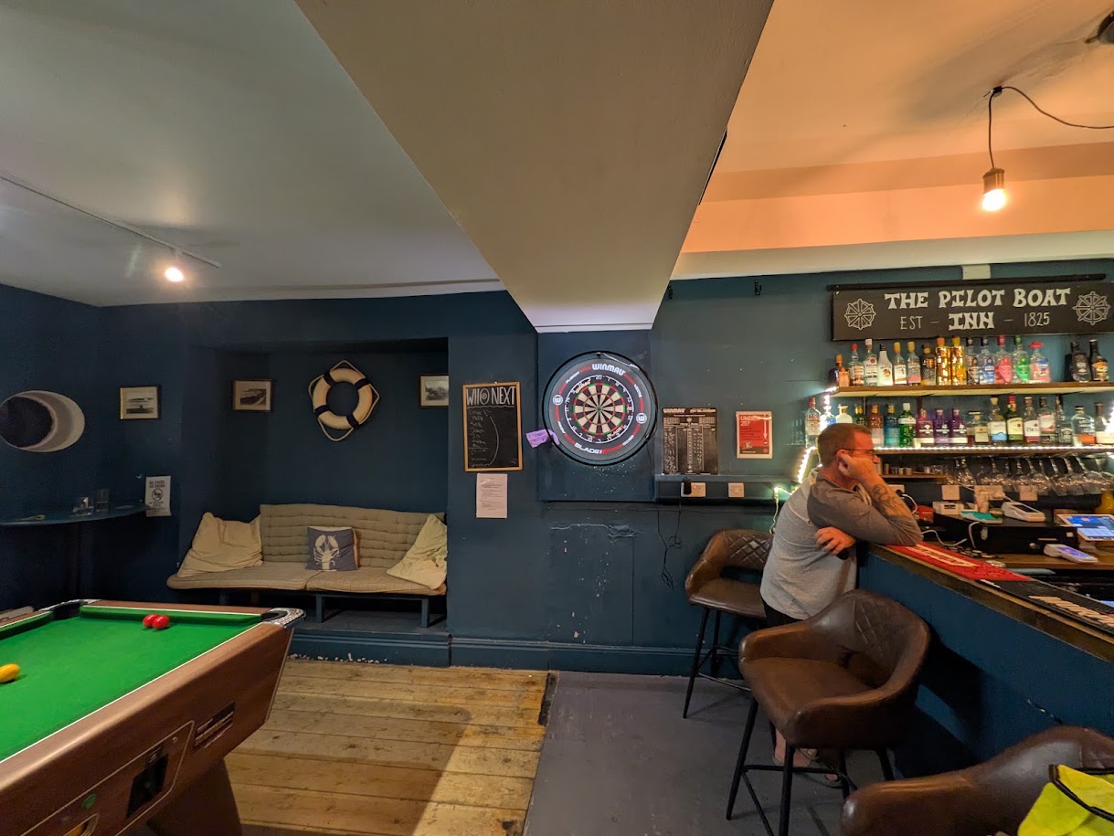 a wide shot of the board showing the oche and a bit of pool table