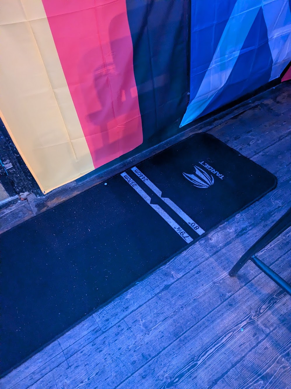 A picture of the oche, a mat on the floor next to a radiator