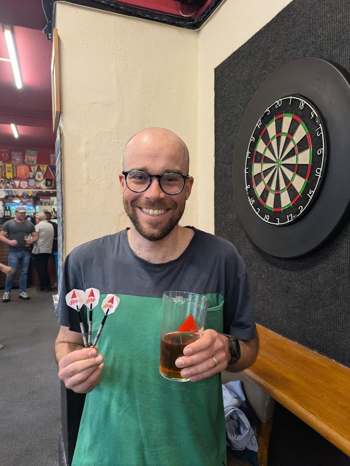 My mate grinning, holding a pint of Bass, and darts with Bass flights
