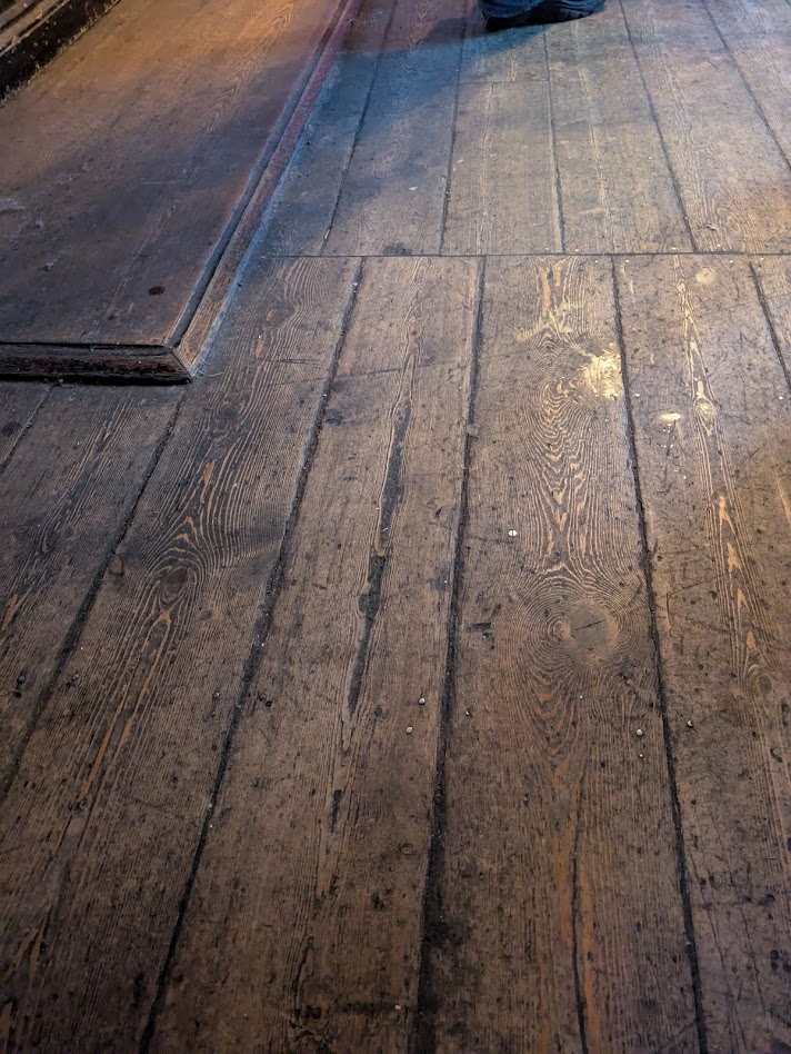 The line of the oche itself, a rough scratched wobbly line in a floorboard.