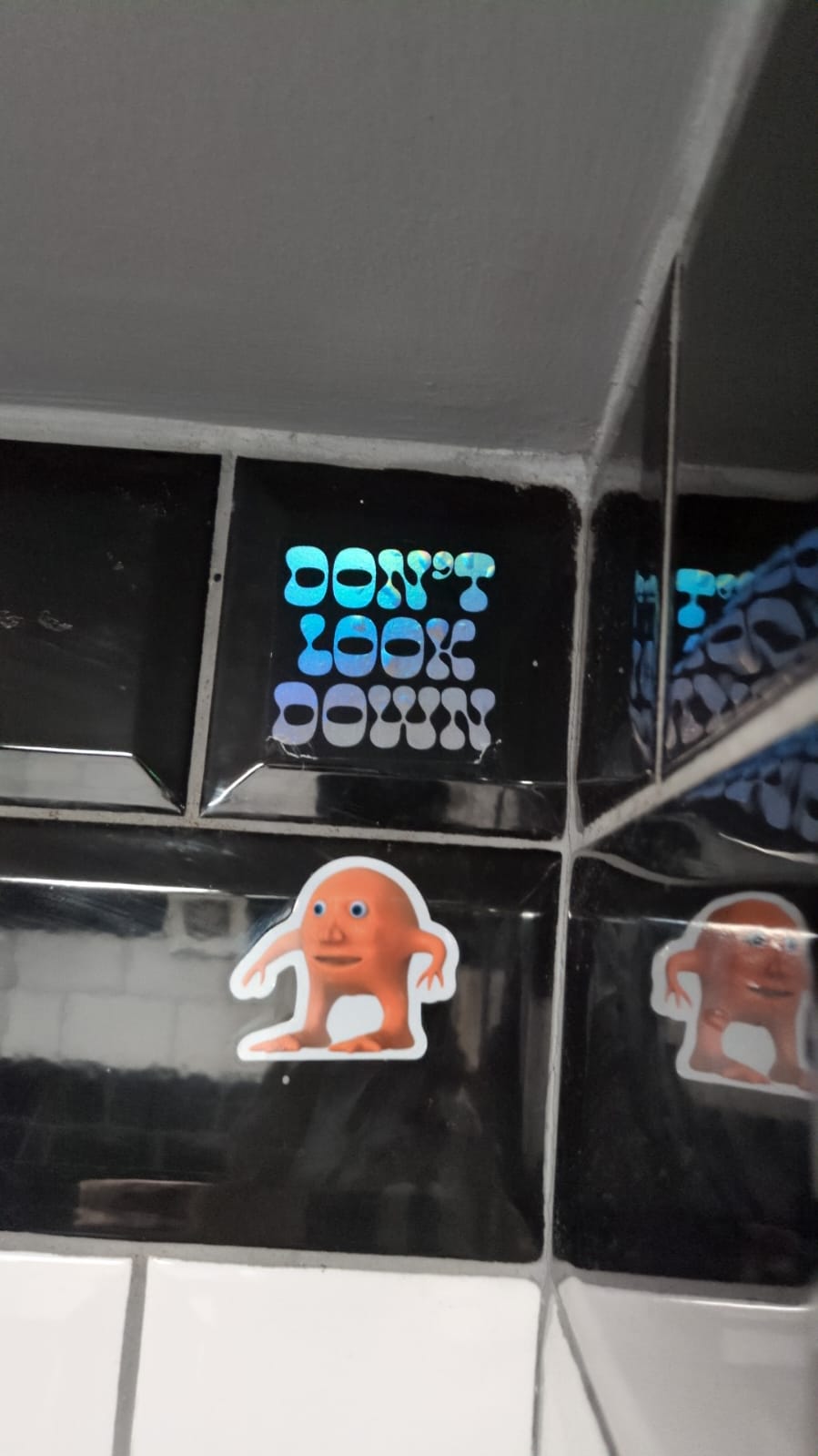 A sticker that says 'don't look down' with orange lad directly underneath