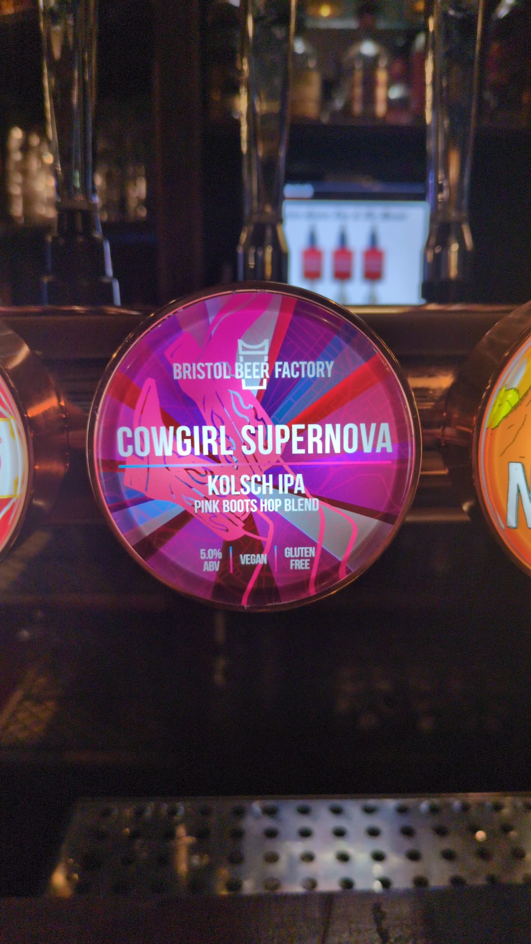 A beer pump clip for Cowgirl Supernova by bristol beer factory. A pink clip with a drawn pair of legs wearing cowboy boots waving in the air